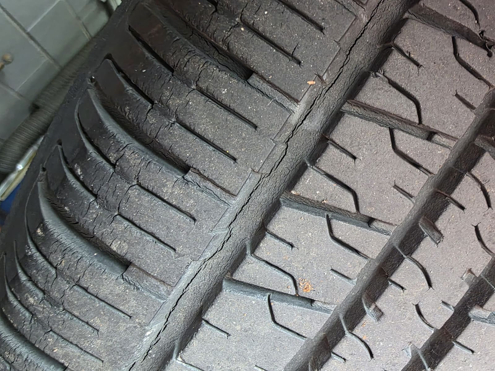 Tire tread with fine cracks through the rubber and a crack running down the centre groove
