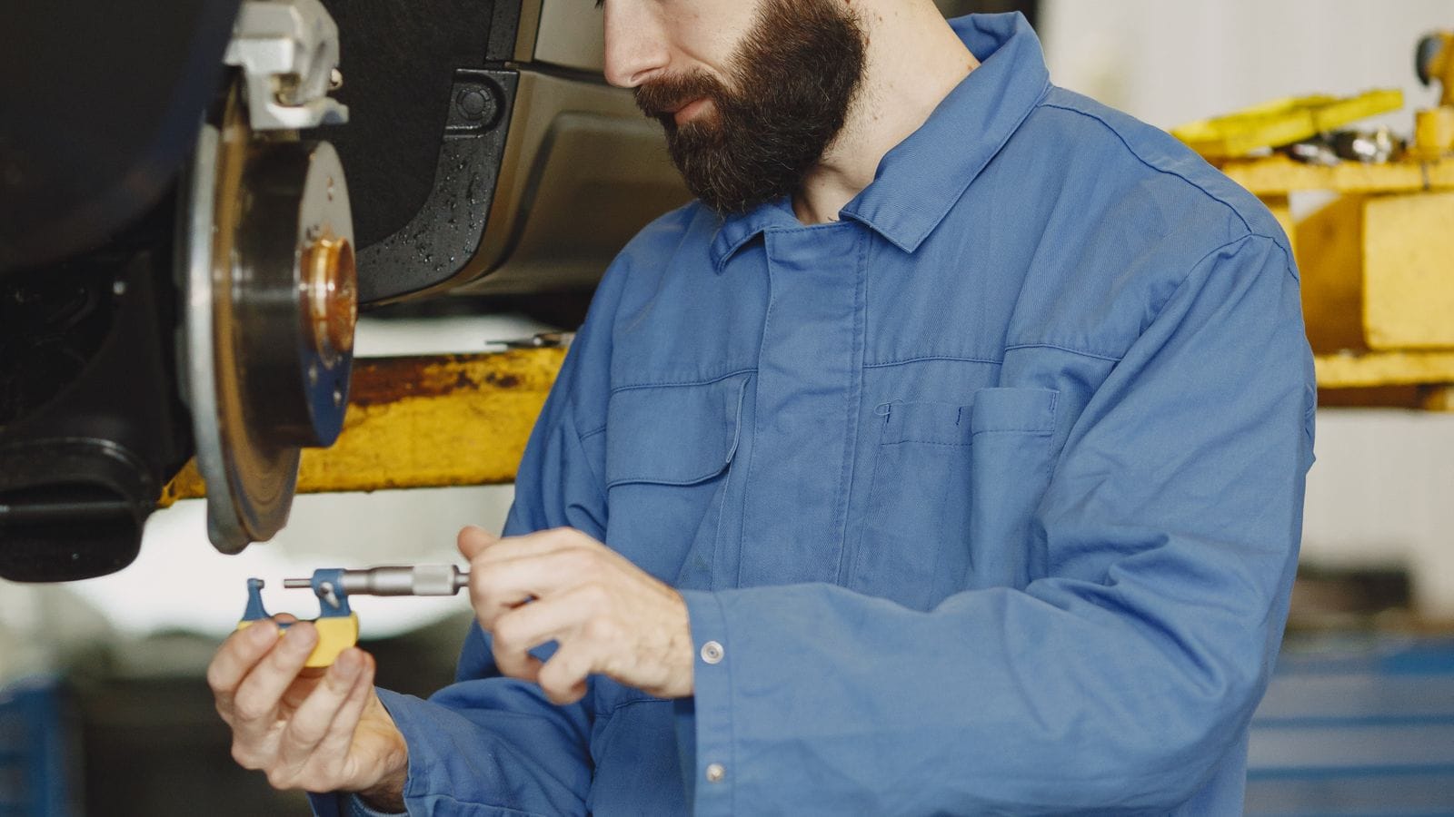 A technician handling a brake pad at the wheel hub