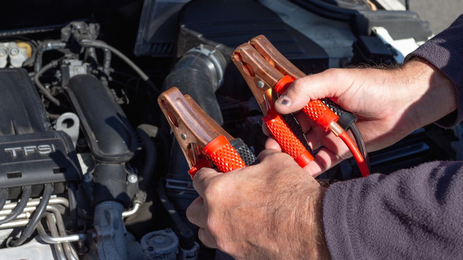 Jumper cables being connected to a car battery