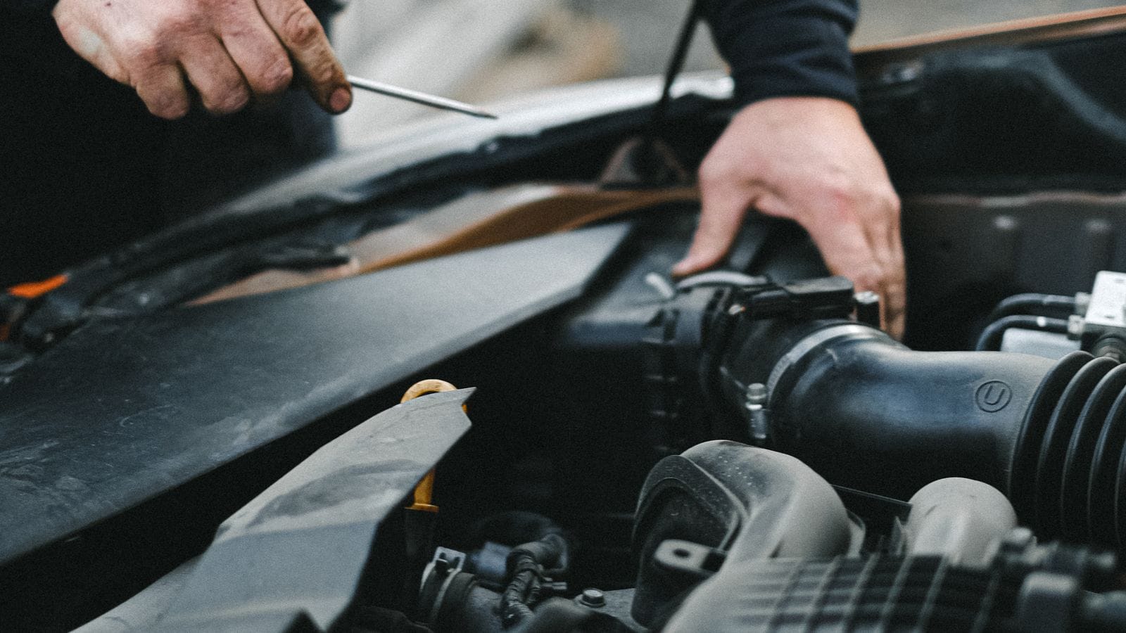 A technician tracing a noise at the engine of a running car